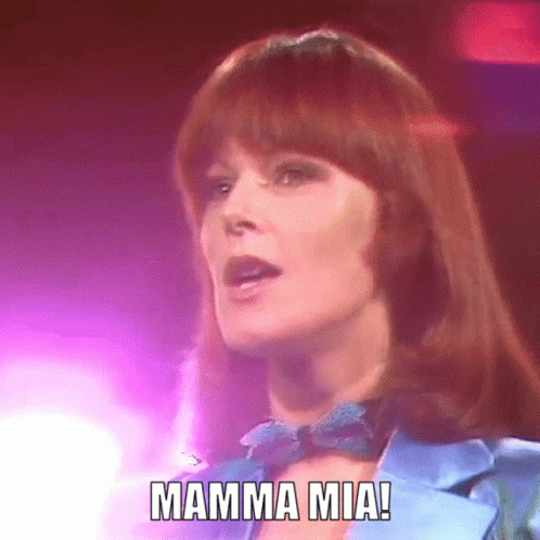 A Woman In A Blue Jacket And Bow Tie Sings Mamma Mia GIF