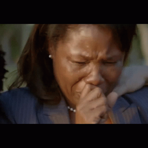 A Woman In A Blue Jacket Is Crying And Covering Her Mouth With Her Hand GIF