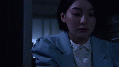 A Woman In A Blue Jacket Is Holding An Origami Bird GIF