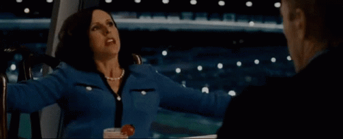 A Woman In A Blue Jacket Is Sitting Next To A Man In A Suit GIF
