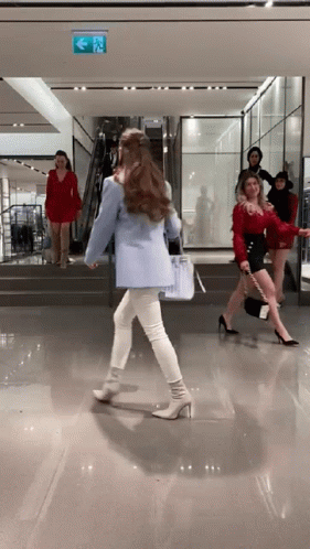A Woman In A Blue Jacket Is Walking Down Stairs In A Store GIF