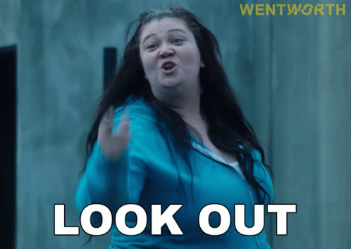 A Woman In A Blue Jacket Says Look Out In White Letters GIF