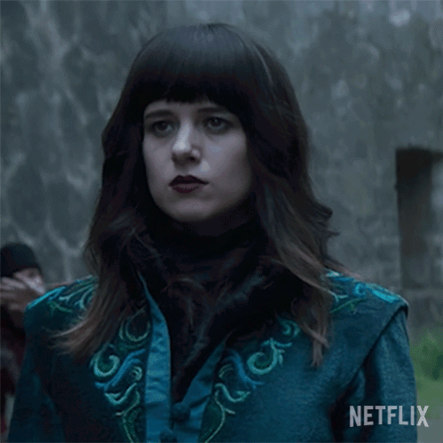 A Woman In A Blue Jacket Says " Now " In White Letters GIF