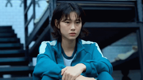 A Woman In A Blue Jacket Sits On Stairs GIF