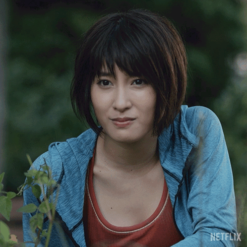 A Woman In A Blue Jacket With Netflix Written On The Bottom Of Her Shirt GIF