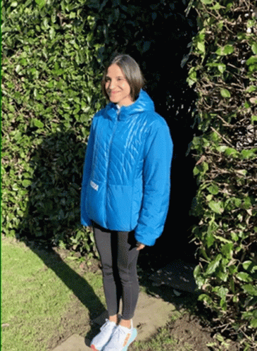 A Woman In A Blue Jacket With The Word Hoka On The Front GIF