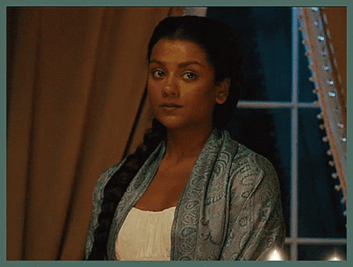 A Woman In A Blue Scarf Is Standing In Front Of A Window . GIF