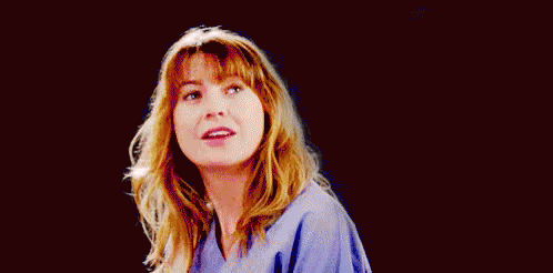 A Woman In A Blue Scrub Is Smiling And Looking At The Camera On A Black Background . GIF