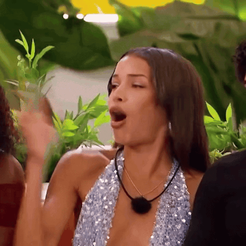 a woman in a blue sequined top is making a funny face with her mouth open