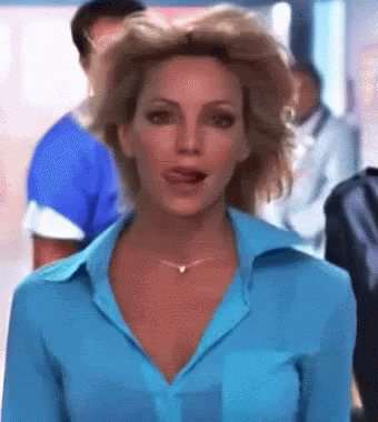 A Woman In A Blue Shirt And Necklace Is Talking To Someone GIF