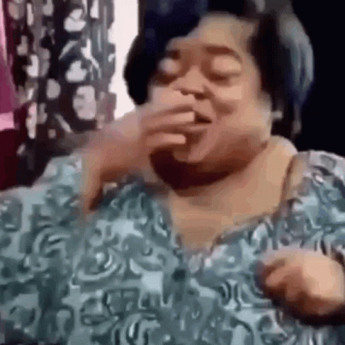 A Woman In A Blue Shirt Is Covering Her Mouth With Her Hand And Laughing . GIF