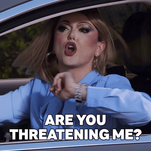 A Woman In A Blue Shirt Is Driving A Car And Says Are You Threatening Me GIF