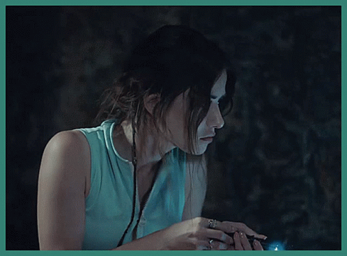 A Woman In A Blue Shirt Is Holding A Flashlight In Her Hand GIF