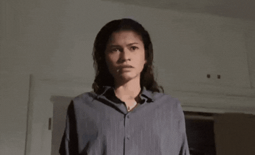 A Woman In A Blue Shirt Is Holding A Knife In Her Hand . GIF