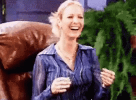 A Woman In A Blue Shirt Is Laughing While Holding A Glass GIF