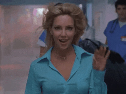 A Woman In A Blue Shirt Is Pointing Her Finger At The Camera GIF