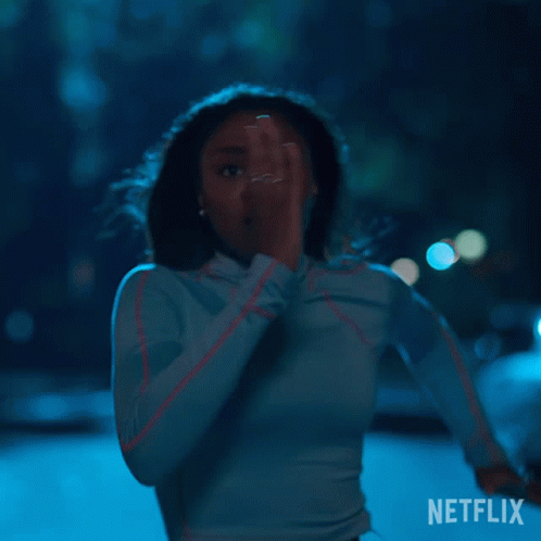 A Woman In A Blue Shirt Is Running In The Dark With A Netflix Logo In The Corner . GIF