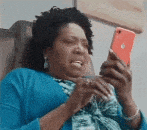 A Woman In A Blue Shirt Is Sitting In A Chair Looking At Her Phone . GIF