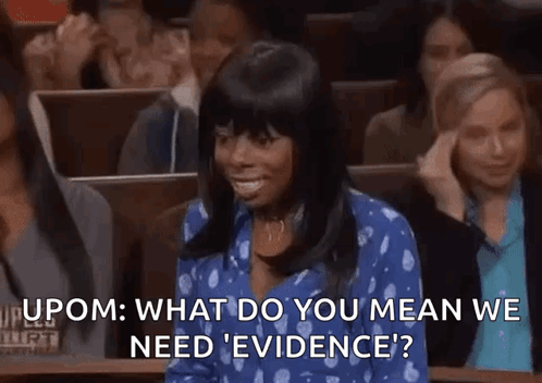 A Woman In A Blue Shirt Is Sitting In A Courtroom With A Crowd Of People . GIF