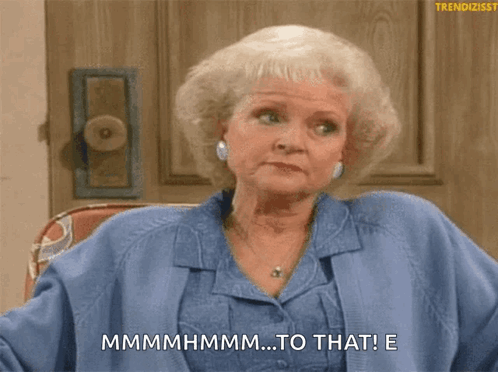 A Woman In A Blue Shirt Is Sitting In Front Of A Door And Says " Mmmmmhmm ... To That ! " GIF
