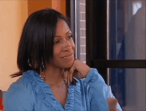 A Woman In A Blue Shirt Is Sitting In Front Of A Window . GIF