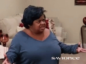 A Woman In A Blue Shirt Is Sitting On A Couch In A Living Room With The Words Savonce On The Bottom GIF