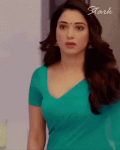A Woman In A Blue Shirt Is Standing In Front Of A Sign That Says Stark . GIF