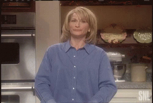 Woman In Blue Shirt Standing In Front Of SNL Logo GIF
