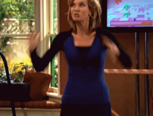 A Woman In A Blue Shirt Is Standing In Front Of A Television Screen GIF