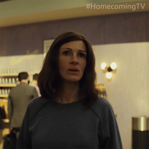 A Woman In A Blue Shirt Is Standing In Front Of A Wall That Says Homecoming Tv GIF