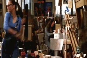 A Woman In A Blue Shirt Is Standing In Front Of An Easel With Mp_if Written On It GIF