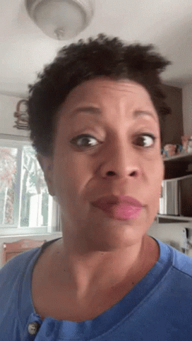 A Woman In A Blue Shirt Looks At The Camera GIF