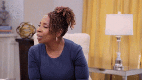 A Woman In A Blue Shirt Sits In A Chair GIF
