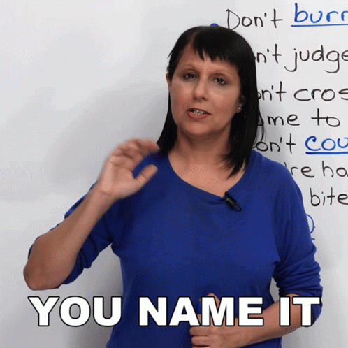 A Woman In A Blue Shirt Stands In Front Of A White Board That Says You Name It GIF