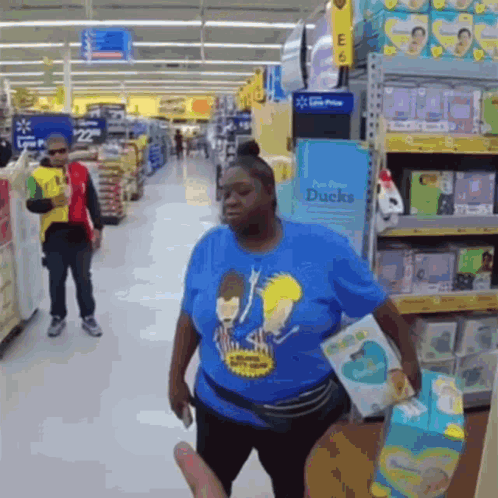 A Woman In A Blue Shirt With Beavis And Butthead On It Is Standing In A Store GIF