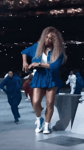 A Woman In A Blue Skirt Is Dancing In A Dark Room GIF