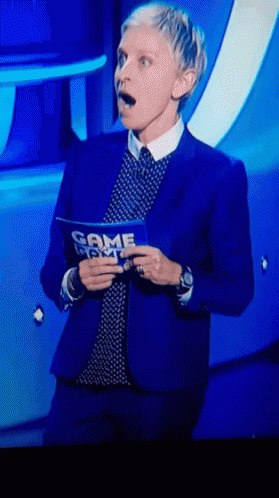 A Woman In A Blue Suit Is Holding A Sign That Says Game Night GIF