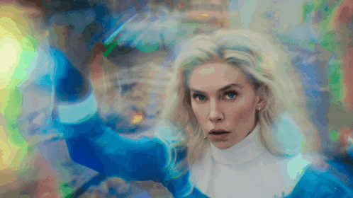 A Woman In A Blue Sweater And White Turtleneck Stands In Front Of A Colorful Background GIF