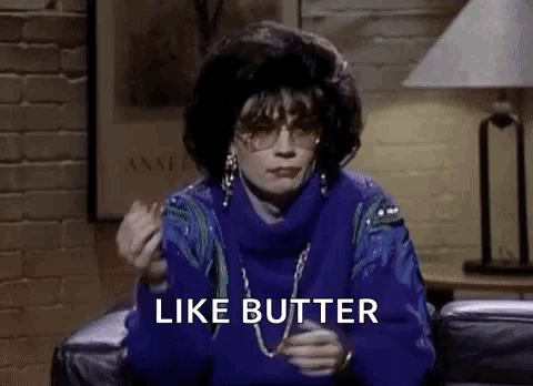 A Woman In A Blue Sweater Is Sitting On A Couch Eating A Piece Of Butter . GIF