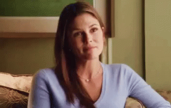 A Woman In A Blue Sweater Is Sitting On A Couch . GIF