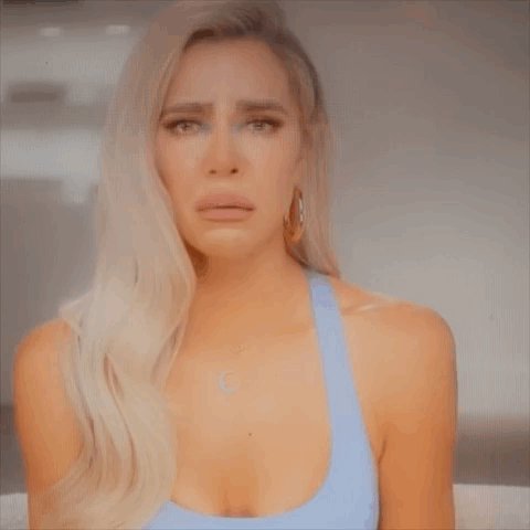 A Woman In A Blue Tank Top Is Crying And Making A Face . GIF