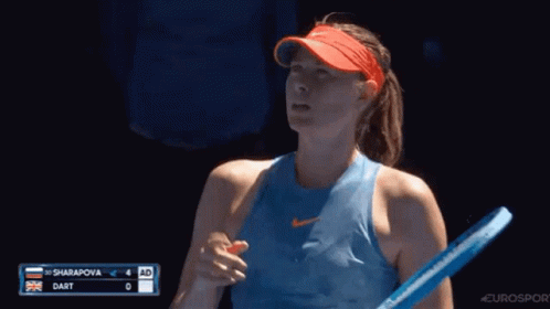 A Woman In A Blue Tank Top Is Holding A Tennis Racquet In Her Hand . GIF