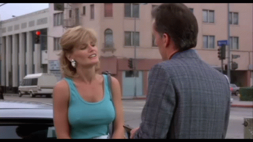 A Woman In A Blue Tank Top Talks To A Man GIF