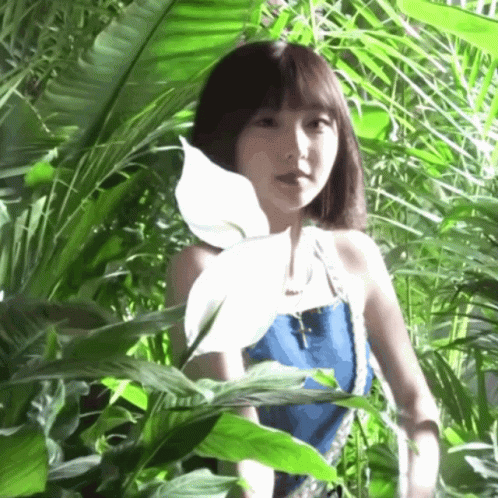 A Woman In A Blue Top Is Standing In A Jungle GIF