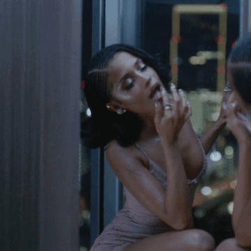 A Woman In A Braided Hairstyle Is Looking At Herself In The Mirror GIF