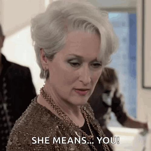 A Woman In A Brown Dress Is Saying She Means You ! GIF