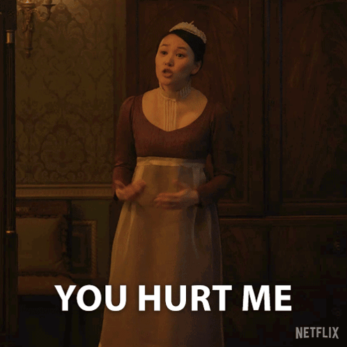 A Woman In A Brown Dress Is Standing In Front Of A Sign That Says You Hurt Me GIF