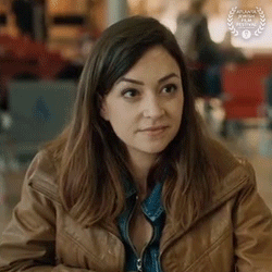 A Woman In A Brown Jacket Is Sitting At A Table In A Restaurant . GIF