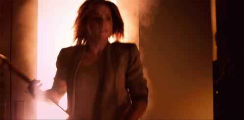 a woman in a brown jacket is walking down stairs in a dark room