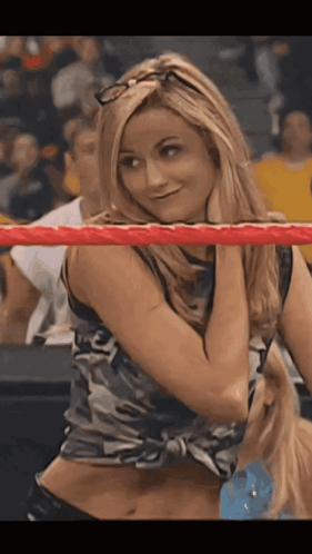 A Woman In A Camo Top Is Standing In A Wrestling Ring GIF
